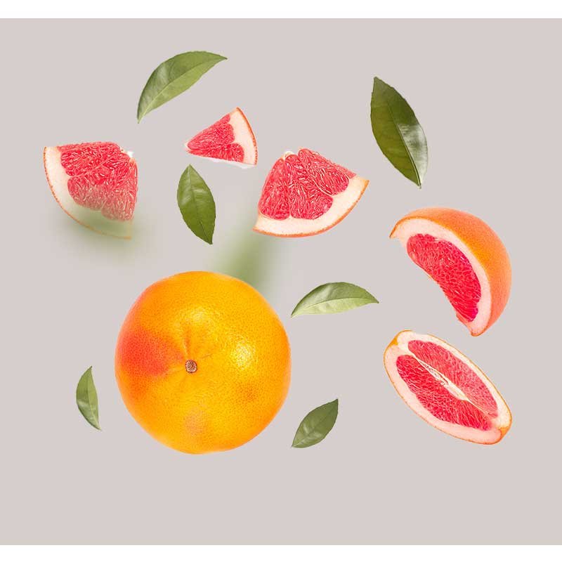 Grapefruit und Grapefruitstücke mit grünen Blättern, symbolisierend die frischen Inhaltsstoffe des Tri-Peelings von RAU Cosmetics, das für sensible Haut zur Tiefenreinigung und Anti-Aging entwickelt wurde.