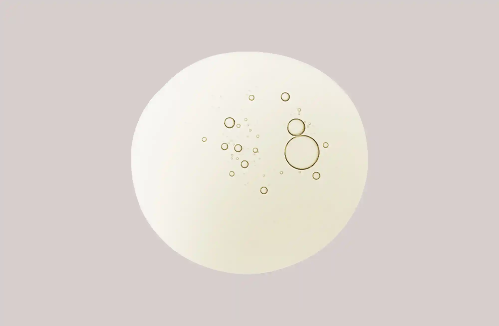 Runde, cremefarbene Oberfläche mit kreisförmigen Blasen; RAU Cosmetics Vitamin A Ampullen-Design für reife Haut.